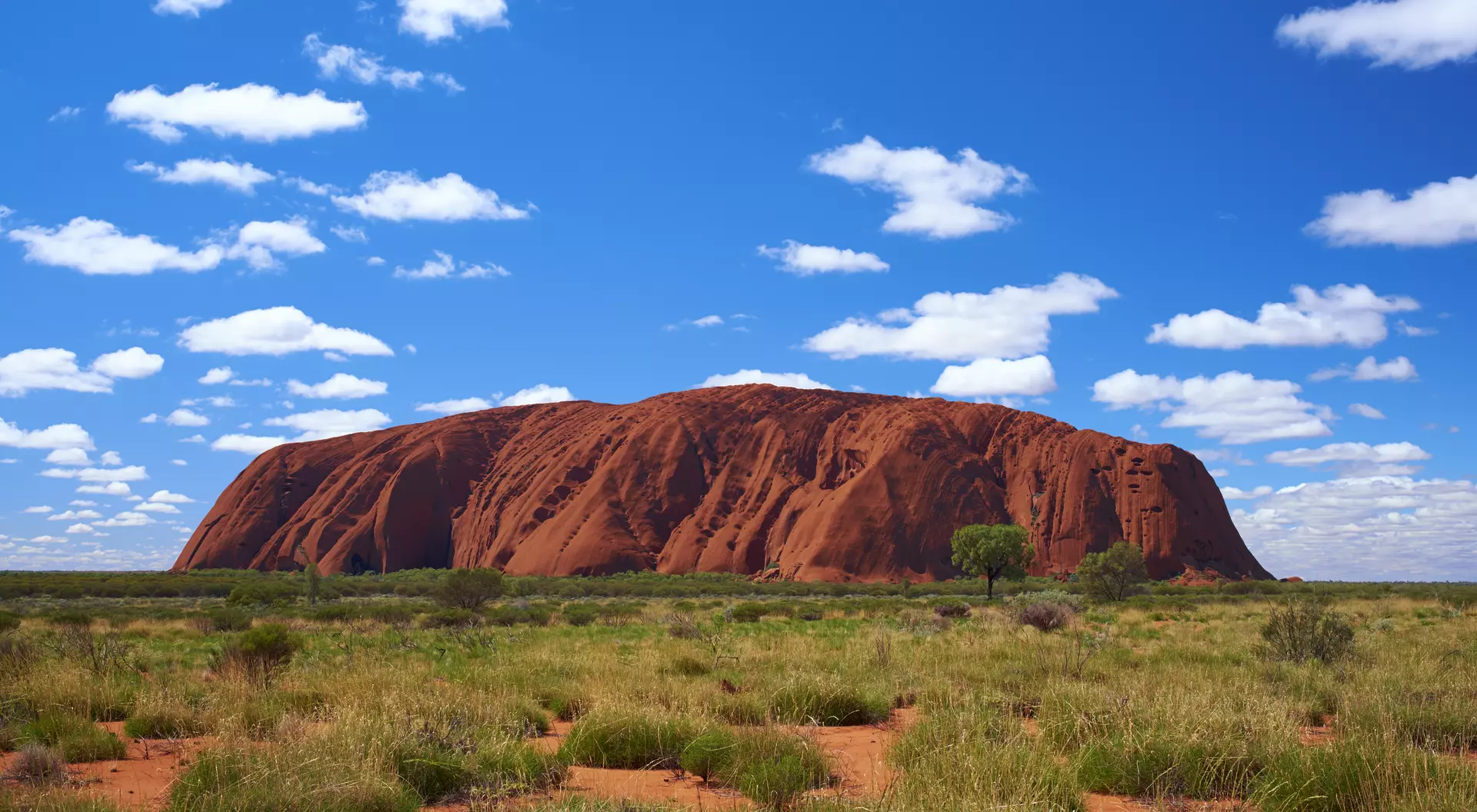Fluffy clouds drift over Uluru (also known as Ayers Rock) in the Australian Outback. A genuine Wonder of the Natural World (and a UNESCO World Heritage Site), it's also a sacred place to the local Anangu people.