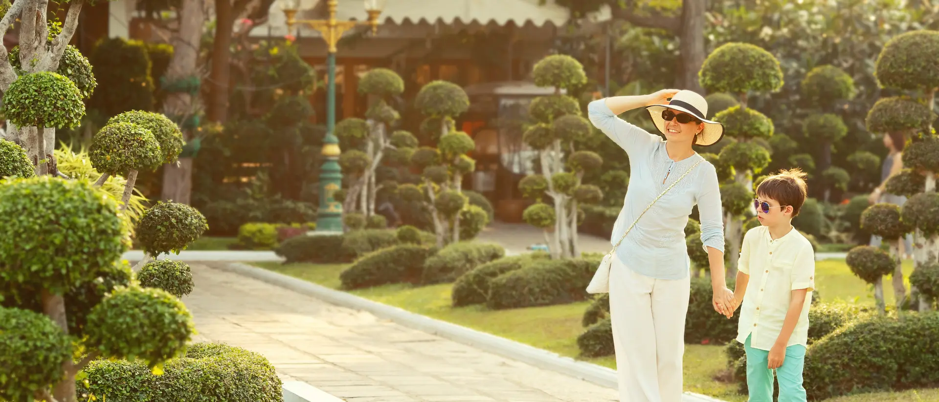 Young mother and her little son walking in Green bonsai trees gardens in Wat Arun, Bangkok, Thailand