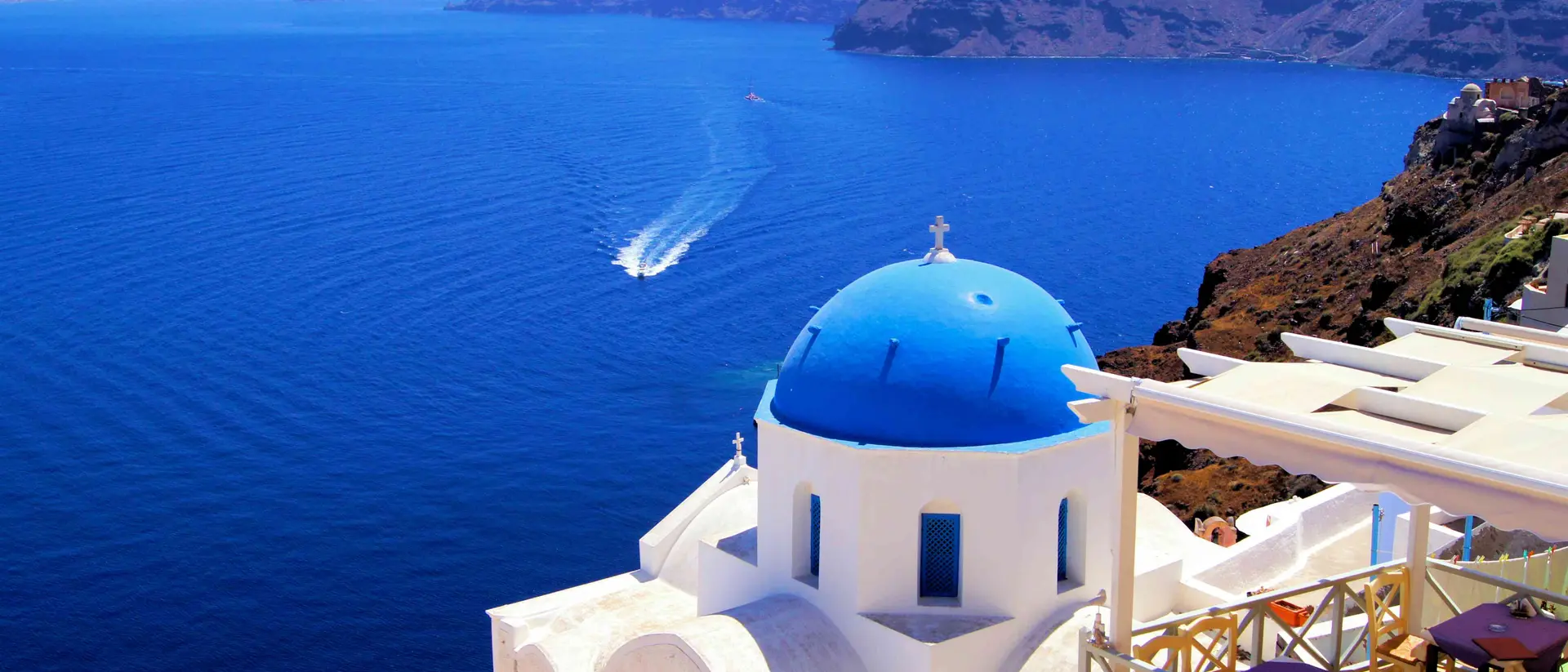 Blue dome church with boat, Oia village, Greece
