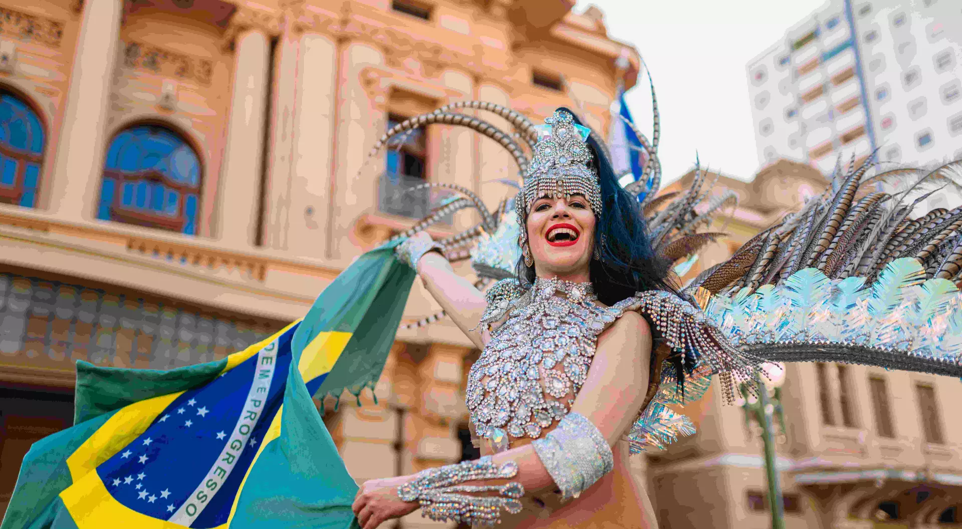 Beautiful Brazilian woman wearing colorful Carnival costume and Brazil flag during Carnaval street parade in city.