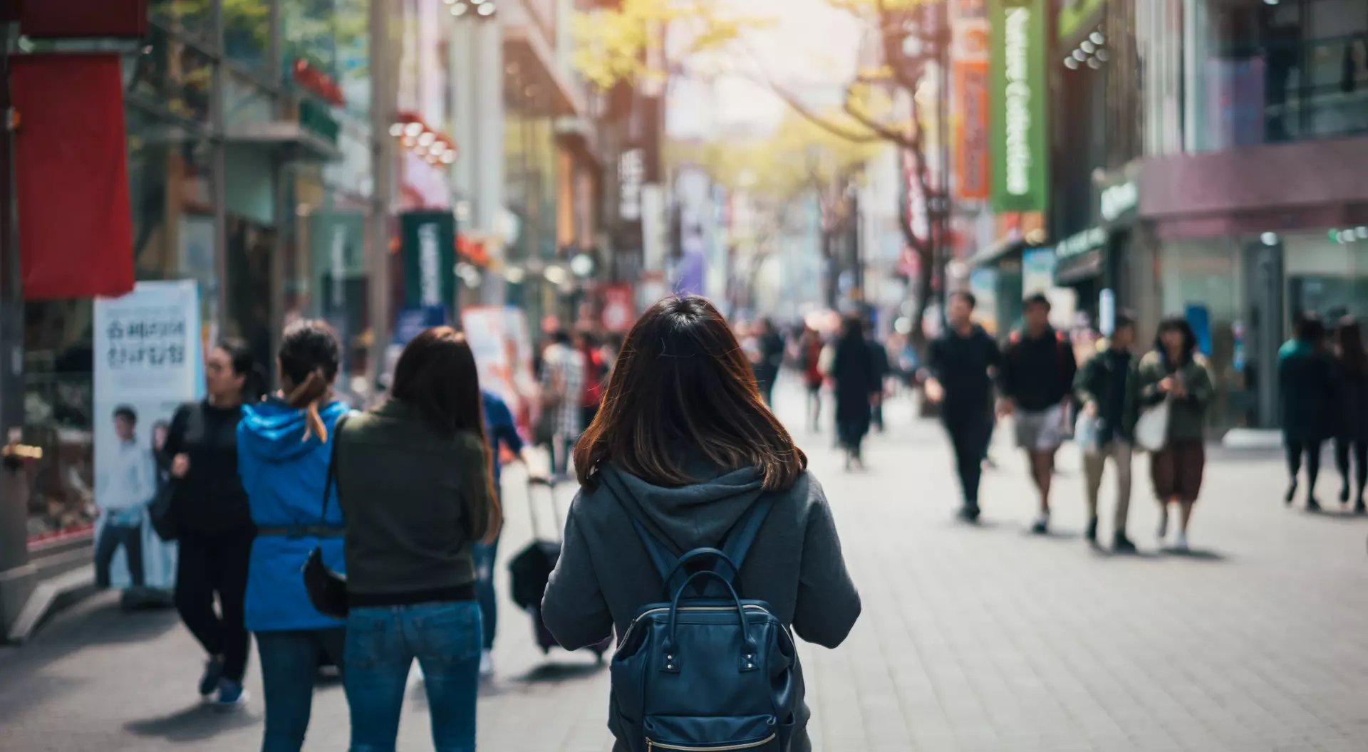 young asian woman walking down a crowded city street
