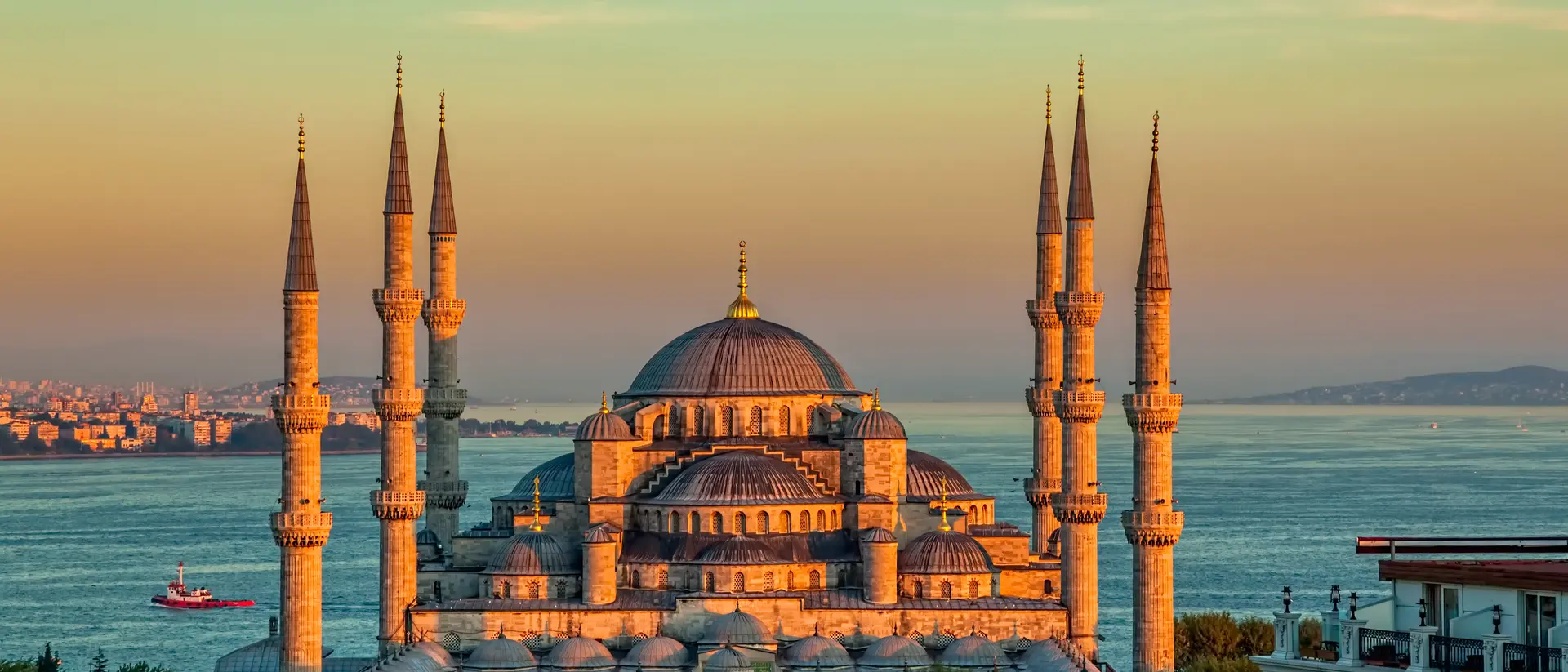 mosque with minarets on edge of water at sunset