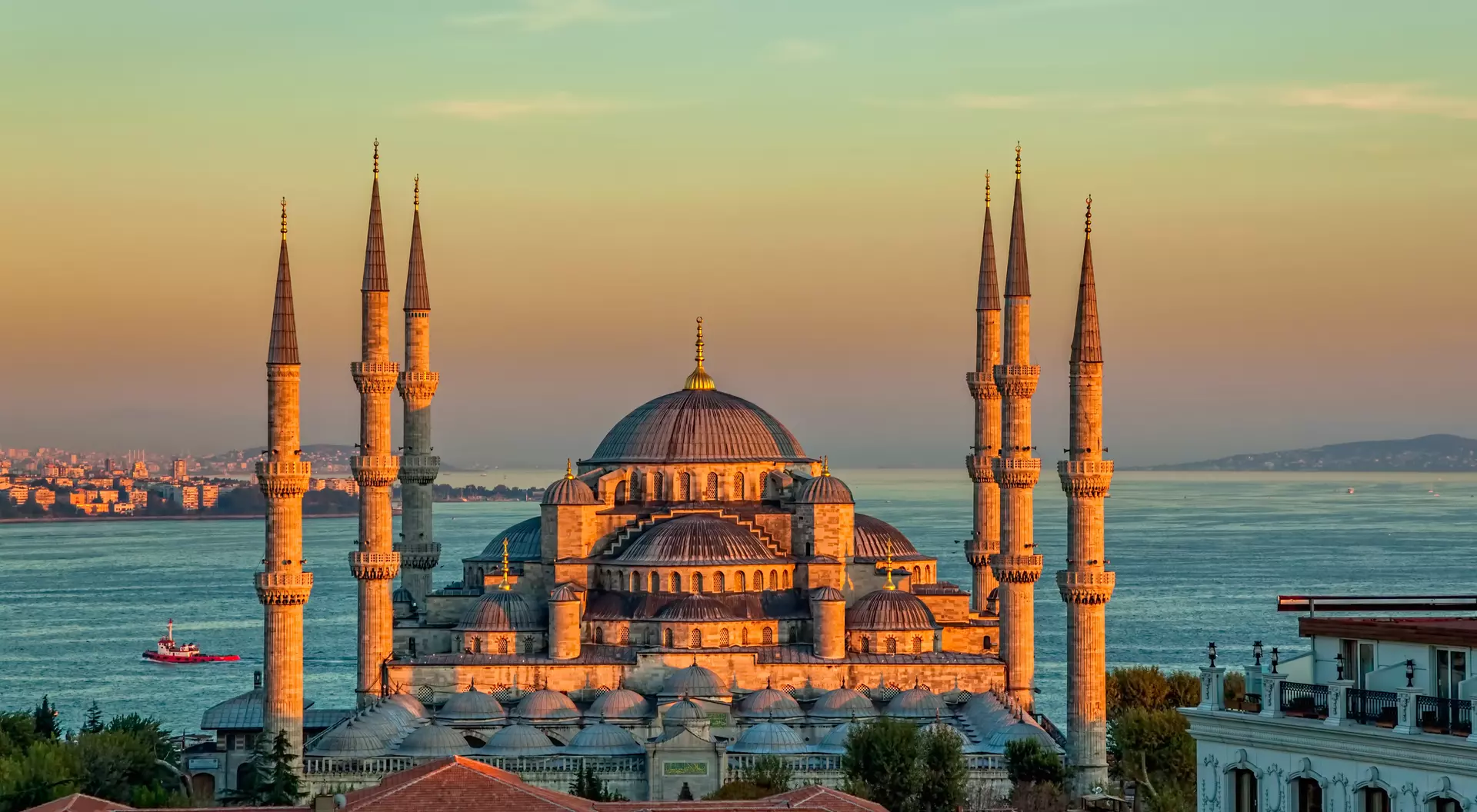 mosque with minarets on edge of water at sunset