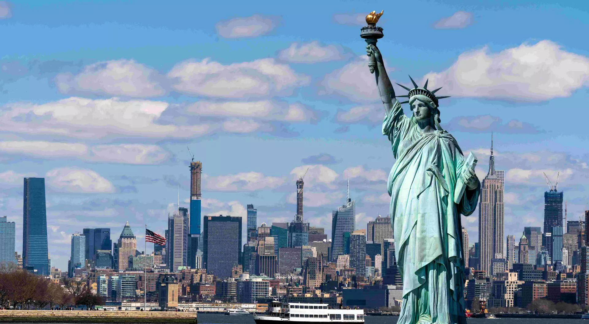 statue of liberty in front of the new york skyline