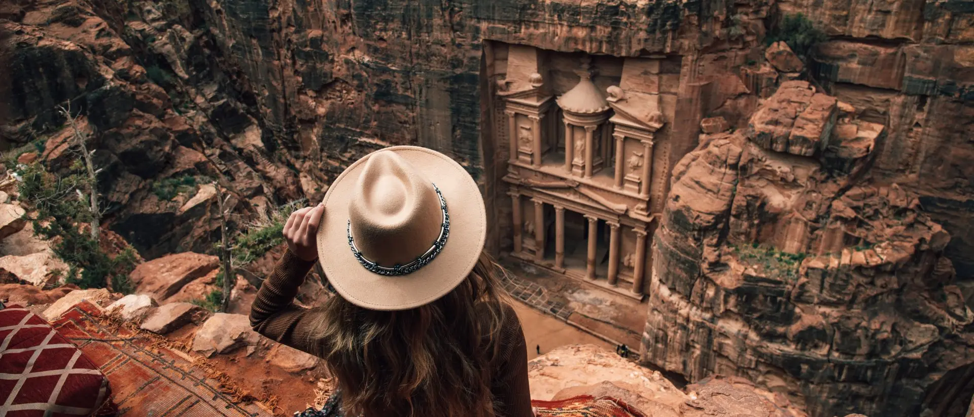 woman sitting on edge of cliff overlooking Petra