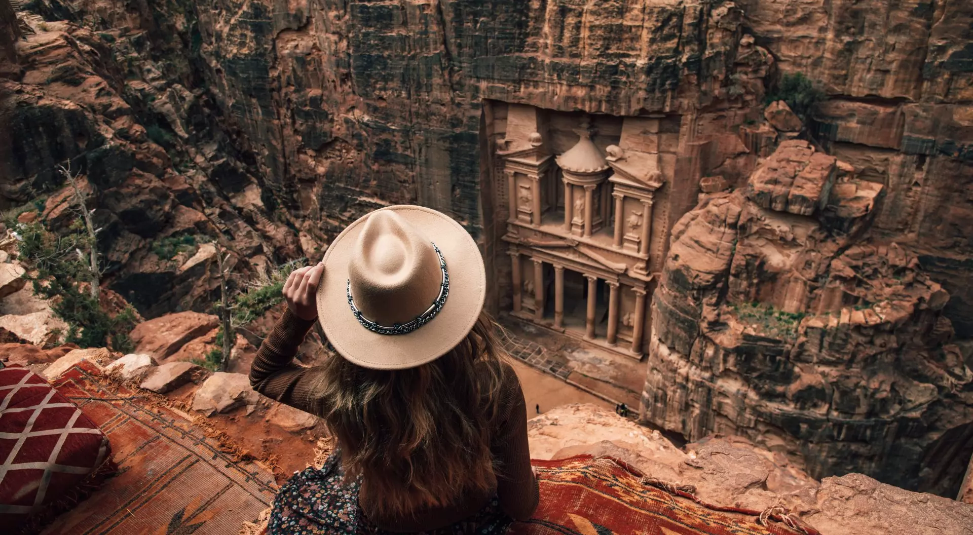woman sitting on edge of cliff overlooking Petra
