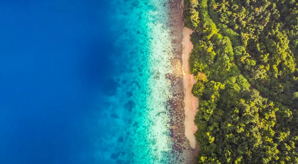 Aerial view of calm aqua marine blue water with tropical secluded beach