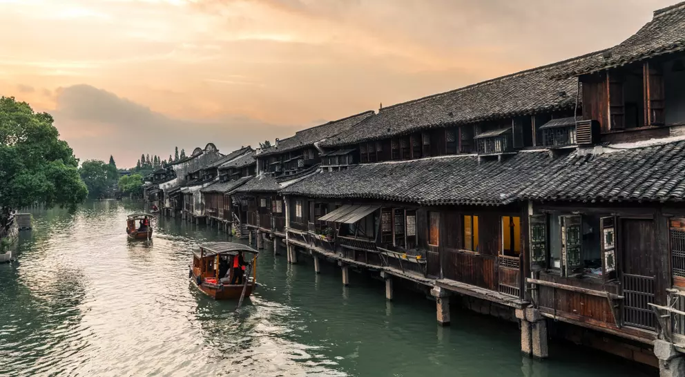 Boats pass by ancient houses along river in Wuzhen, a historic scenic town