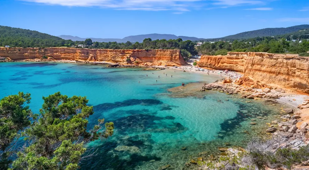 Bright light of a summer noon, transparent waters marbled with Posidonia meadows, sparse bathers on the beach.