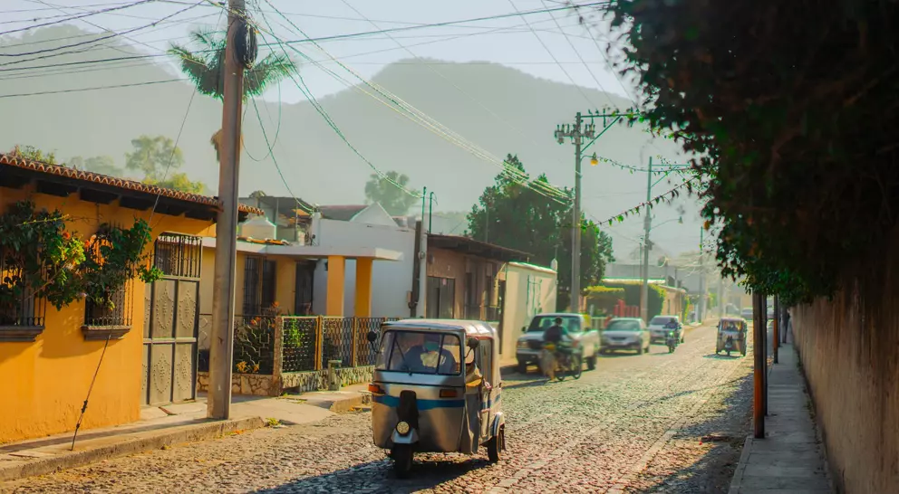 Tuk-tuk three wheeled vehicle driving along historical street in Guatemala