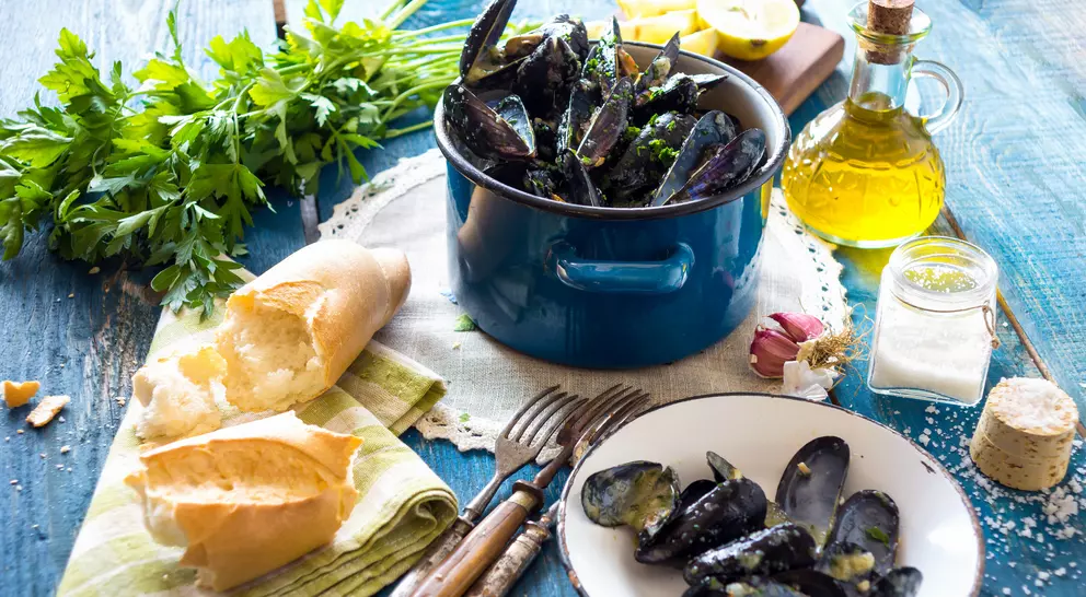 Mussels in Buzara sauce on a table with olive oil and bread