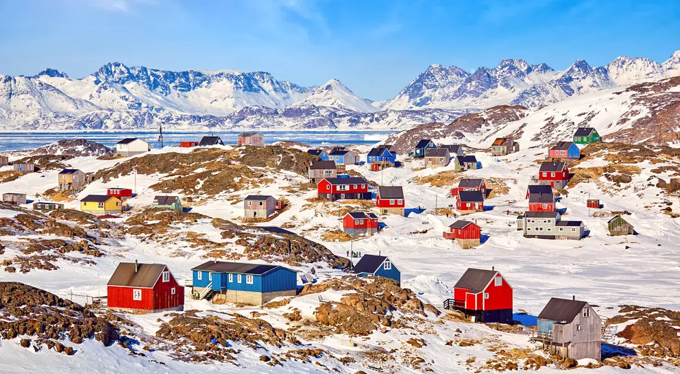 A colourful village in remote Greenland with blue and red houses under a clear and sunny sky in winter