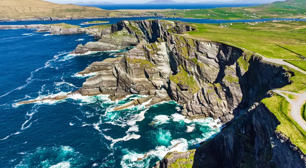 Amazing wave lashed cliffs surrounded be green hills on a sunny day
