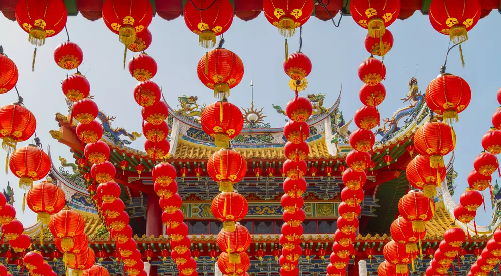 A vibrant display of red lanterns hanging in front of a decorative building, celebrating a festive occasion.
