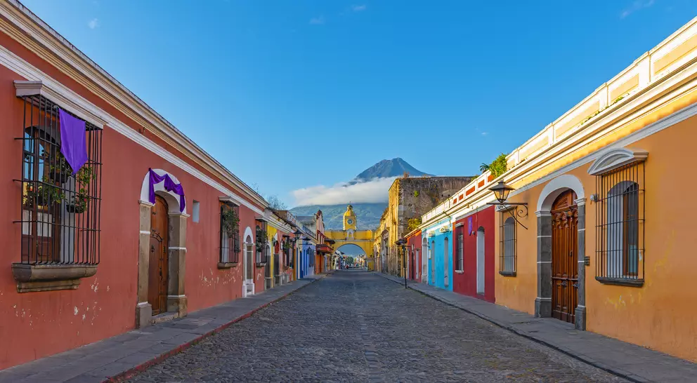 "Colorful main street of Antigua city at sunrise with the famous yellow arch and the Agua volcano in the background "