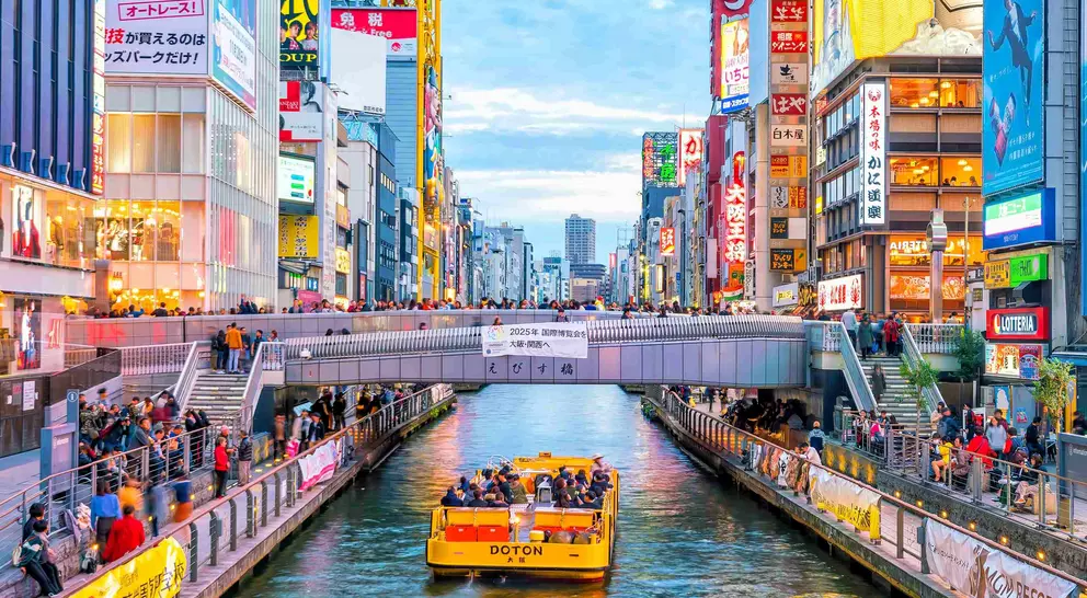Boat floating down canal on Dotonbori shopping street, a famous destination for traveling and shopping in Osaka
