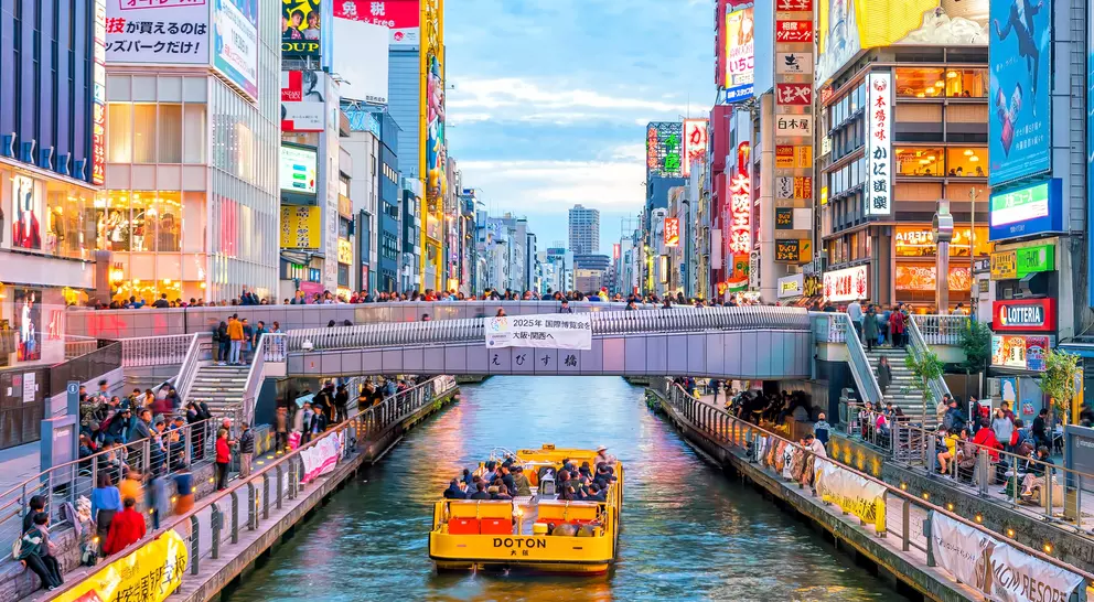 Boat floating down canal on Dotonbori shopping street, a famous destination for traveling and shopping in Osaka