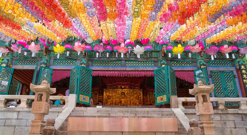 A temple entrance adorned with colorful lanterns hanging from above, creating a vibrant and festive atmosphere.
