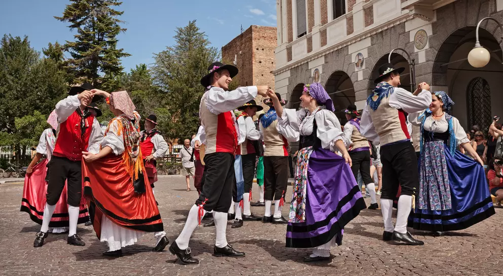 A traditional dance performance with performers in colorful costumes, set in a lively outdoor space.