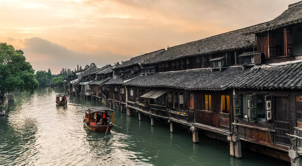 Boats pass by ancient houses along river in Wuzhen, a historic scenic town
