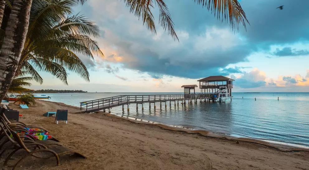 A pier and hut jut out onto the blue calm waters