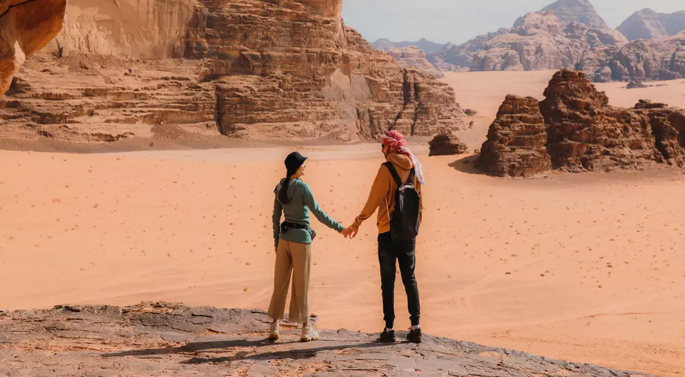 Young woman and man traveler contemplating the scenic landscape of Wadi Rum desert