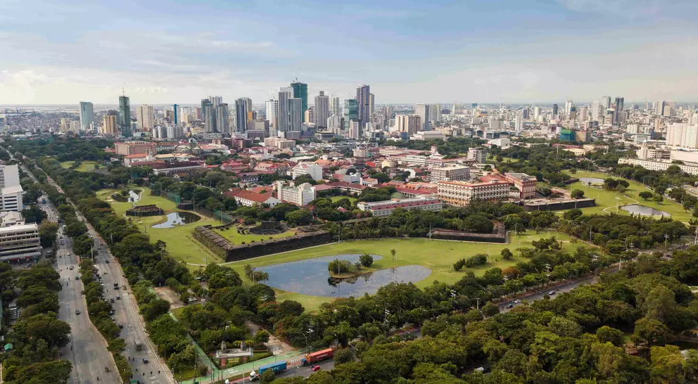 Aerial of Intramuros, an old historic walled city, surrounded by golf courses, and Manila skyline in background
