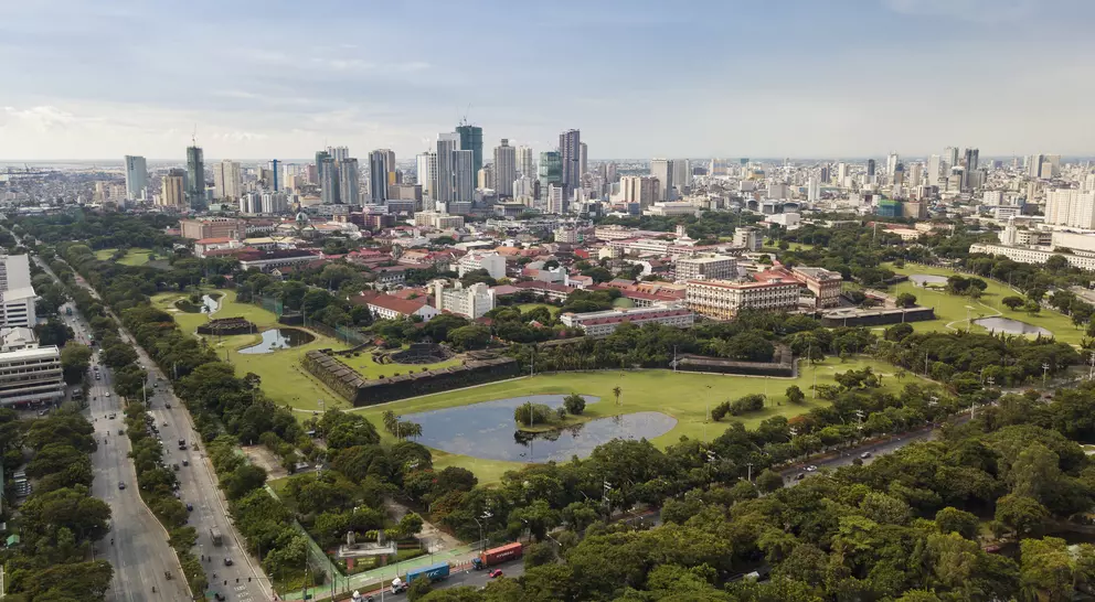 Aerial of Intramuros, an old historic walled city, surrounded by golf courses, and Manila skyline in background