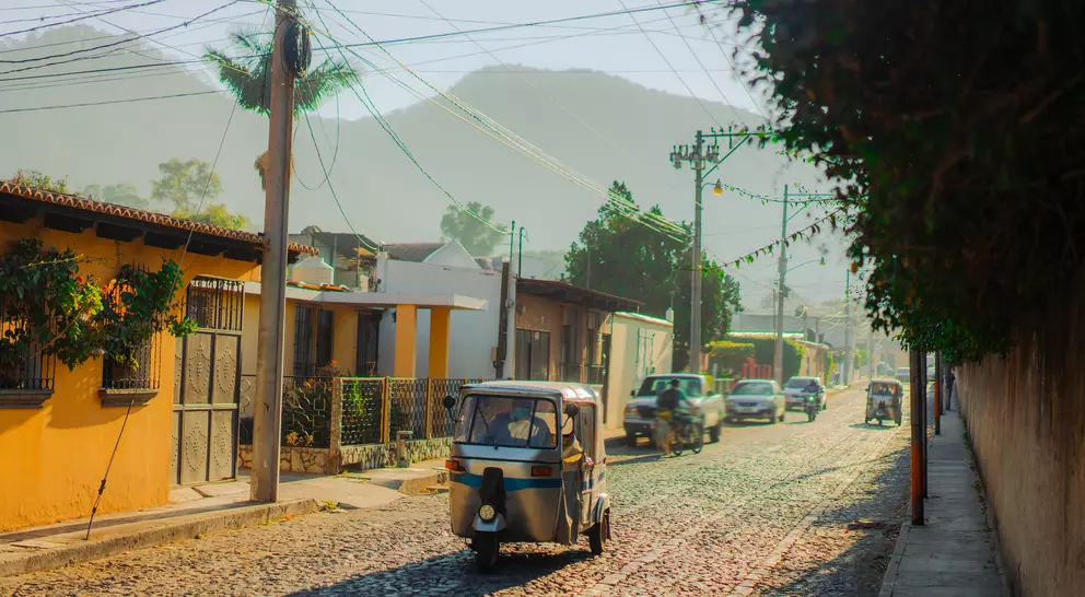 Tuk-tuk three wheeled vehicle driving along historical street in Guatemala