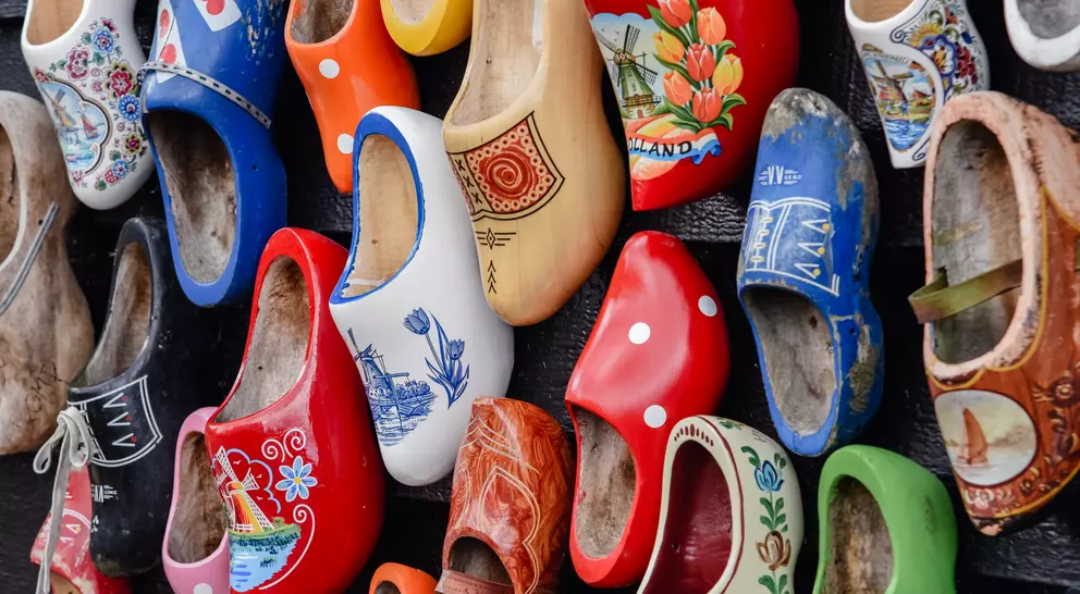 Colorful decorative wooden shoes arranged on a wall, showcasing various patterns and designs.
