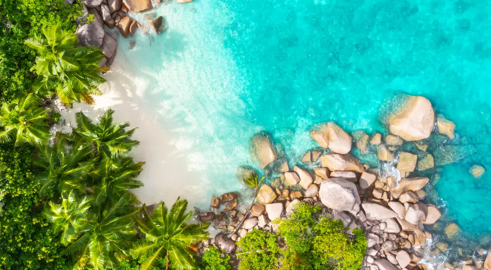 Aerial view from above of beach and bright blue waters of coastline