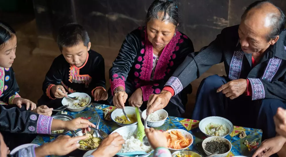 A family sits together sharing a meal, enjoying traditional dishes in a warm, cozy setting.
