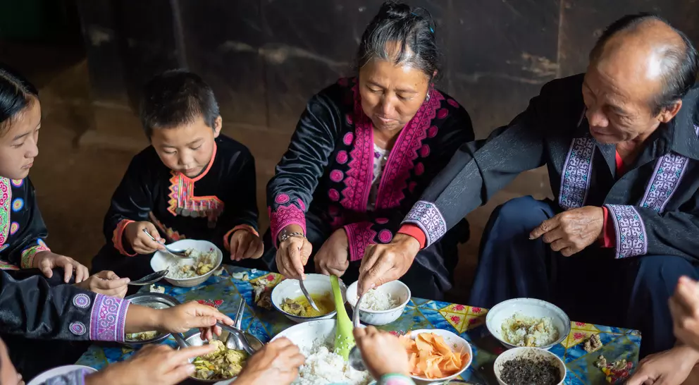 A family sits together sharing a meal, enjoying traditional dishes in a warm, cozy setting.