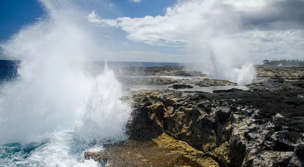 The Alofaaga Blowholes send water towards the bright blue sky along the ocean in Somoa