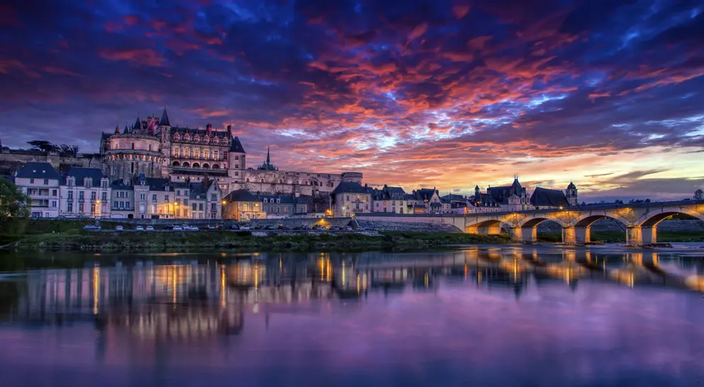 The royal chateau and ancient bridge with a vivid sunset in the background