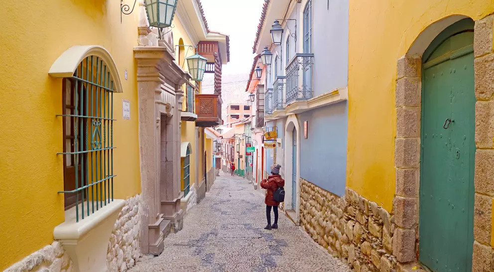 Colorful narrow street lined with buildings; a person stands in the distance, surrounded by vibrant walls and lanterns.