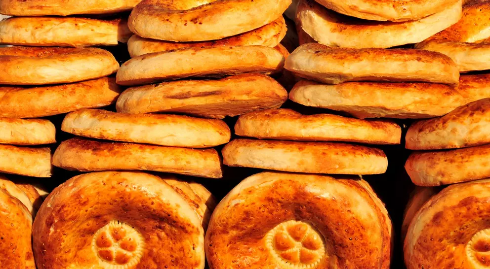A stack of freshly baked round bread, golden brown with a slightly crisp surface and a decorative pattern on top.