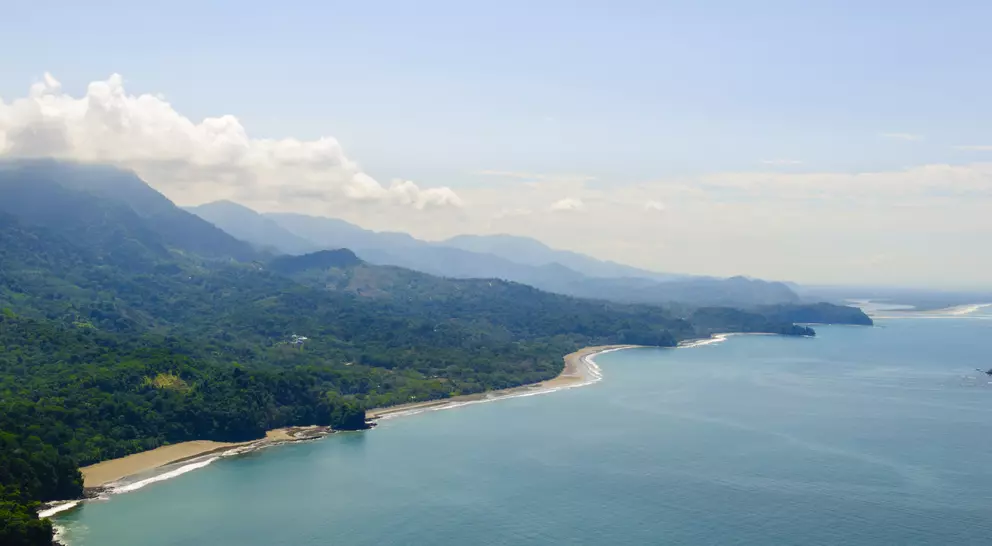Vibrant tropical forests flow down from the mountains to the sandy beaches along the coast. Aerial view of the Costa Ballena near Dominical, Costa Rica