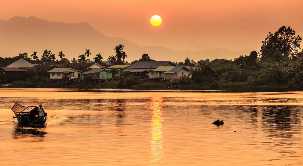 Sunset along the river  with a local village and mountains in the background