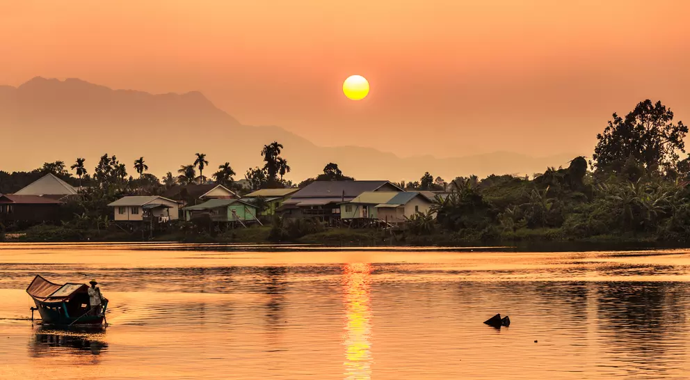 Sunset along the river  with a local village and mountains in the background