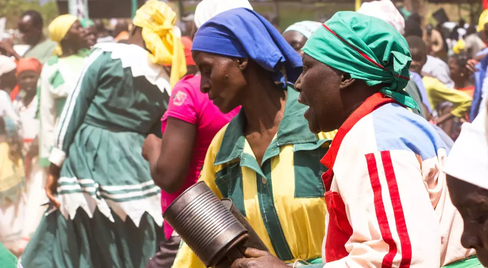 A vibrant scene of people dancing and celebrating, wearing colorful traditional attire at a lively outdoor event.