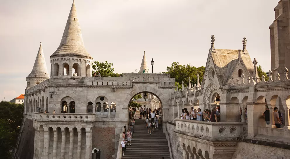 Hungarian Fisherman's Bastion with gothic towers, steps, and visitors under a cloudy sky.
