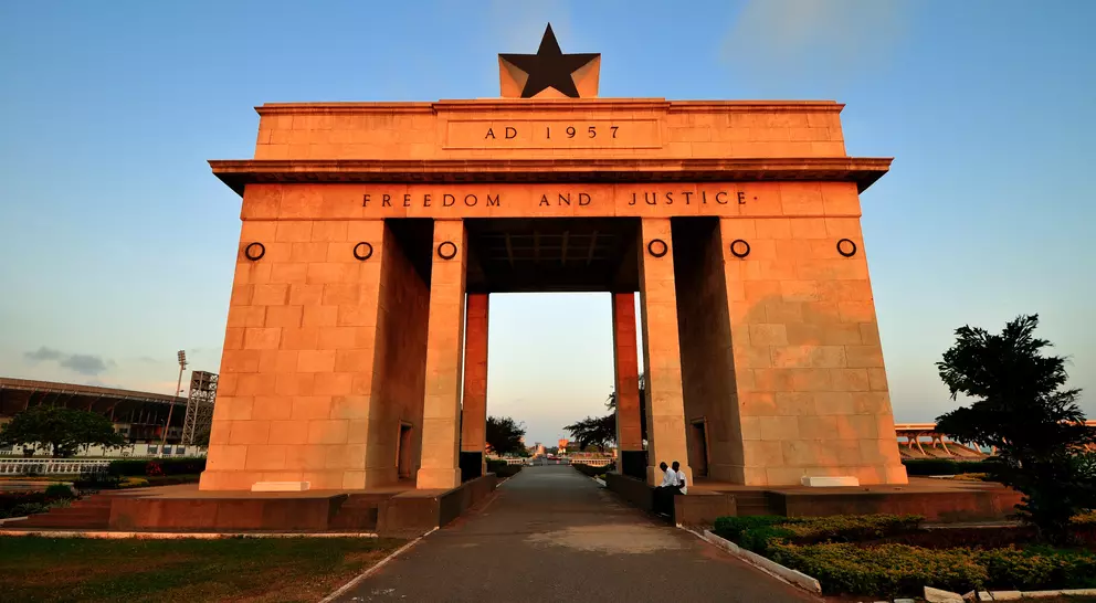 Gateway arch with a star on top, inscribed "Freedom and Justice," set in a landscaped area during sunset.