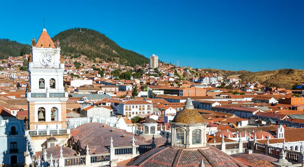 View of white colonial cathedral clocktower and red roofs in Sucre, Bolivia known as the White City
