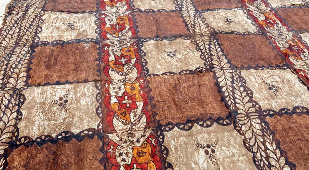 Patterned fabric with alternating brown and beige squares, featuring stylized floral designs and intricate borders.