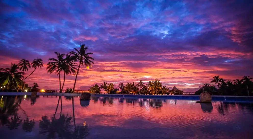 Vibrant and colourful sunset over bungalows and palm trees
