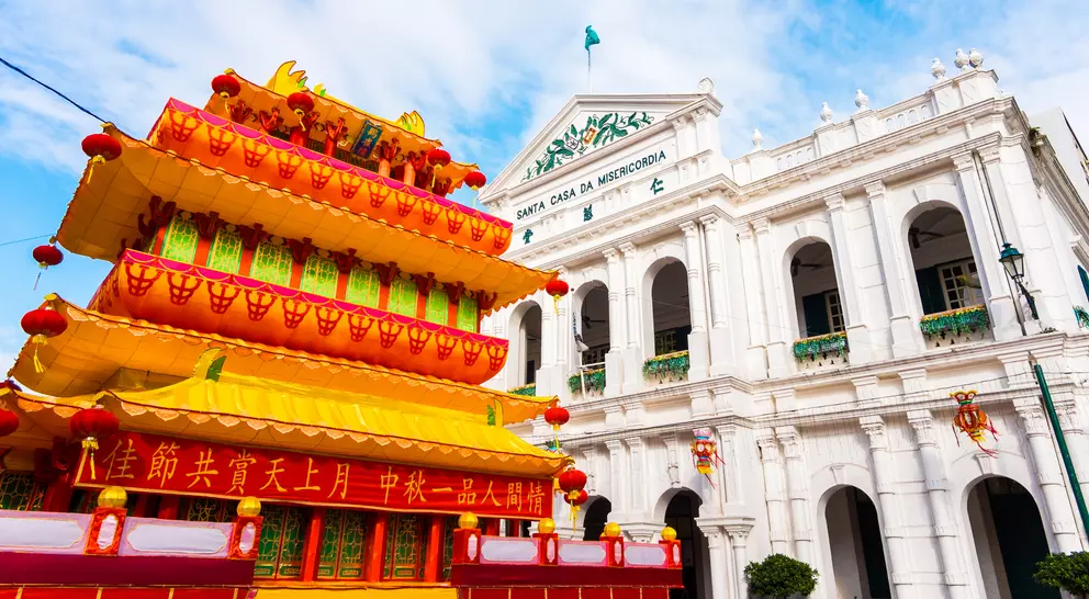 Colorful traditional decoration in front of a white colonial building, under a bright blue sky.