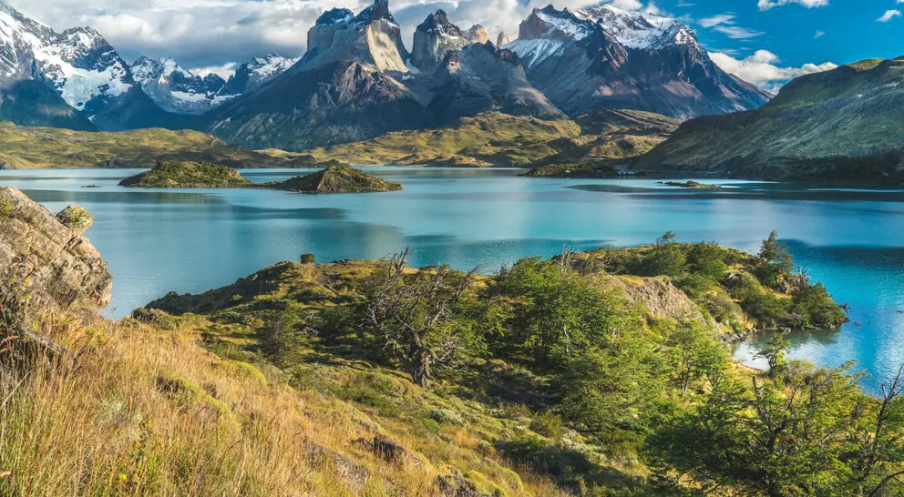 Blue lake on a snowy mountains background and cloudy sky