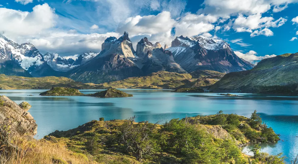Blue lake on a snowy mountains background and cloudy sky
