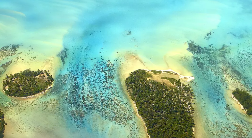Sandy turquoise tropical beach, motus and reefs aerial view